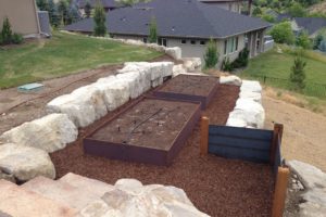 Custom built, raised garden beds surround by boulder retaining walls.